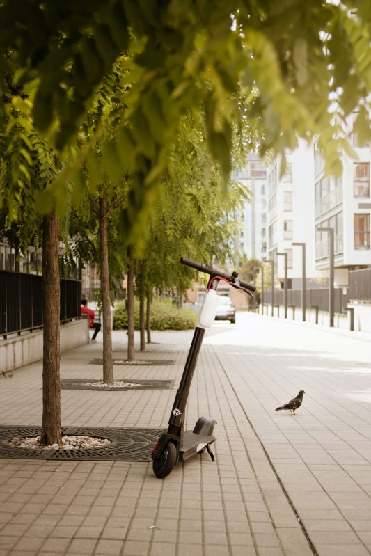 Black electric scooter parked on sidewalk