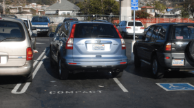 Photo an SUV parked badly in a spot labeled for compact cars