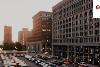 Parking lot full of cars near buildings of different heights