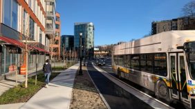 Person walking on sidewalk next to bike lane and bus lane